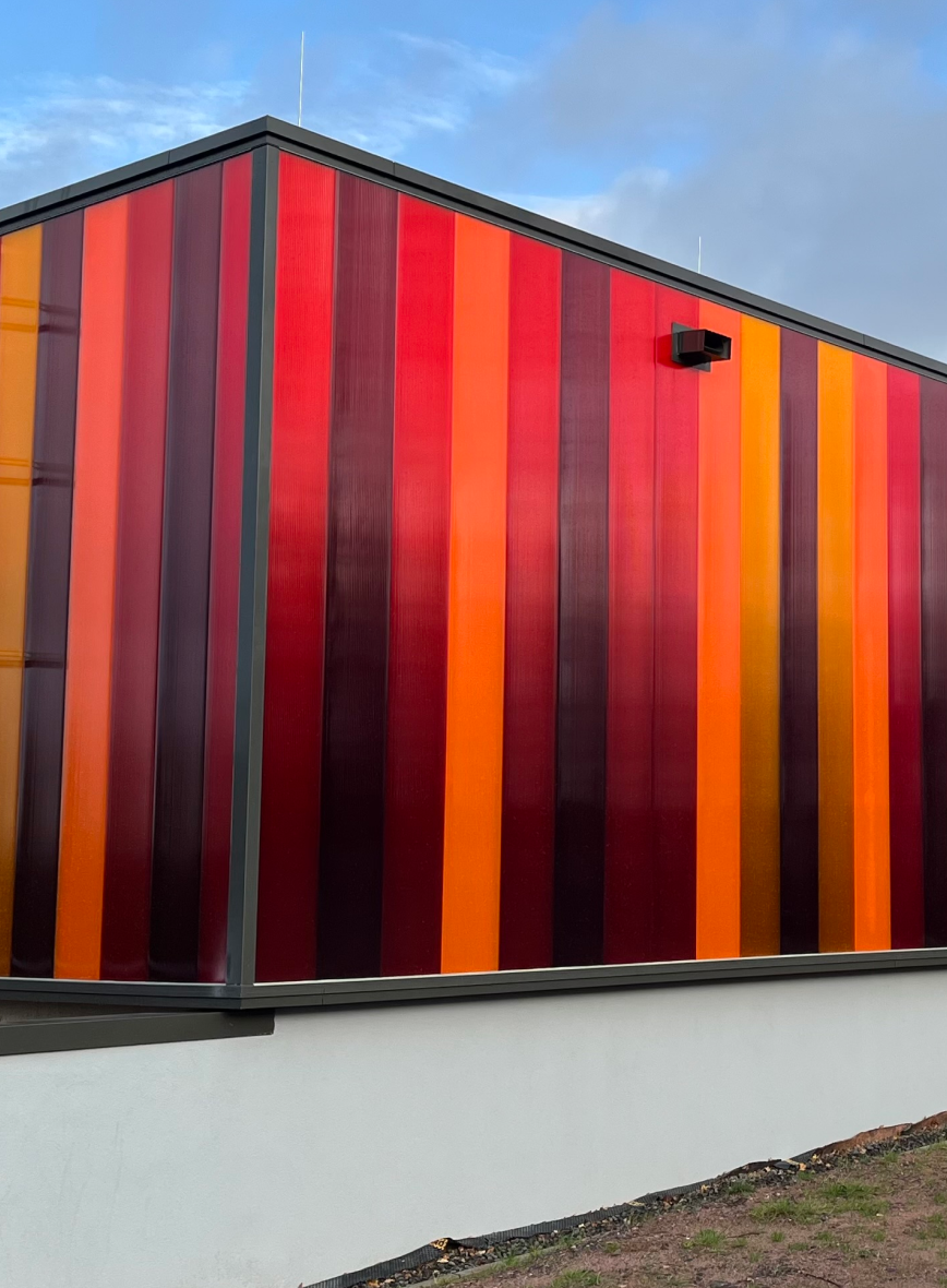 Facciata realizzata con pareti in policarbonato colorato, soluzione moderna e luminosa per l’edilizia industriale e architettonica.